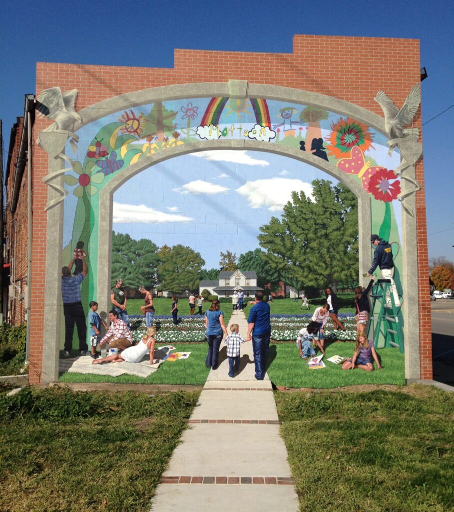 Picture of mural painted on brick wall, depicting people outside a white farmhouse